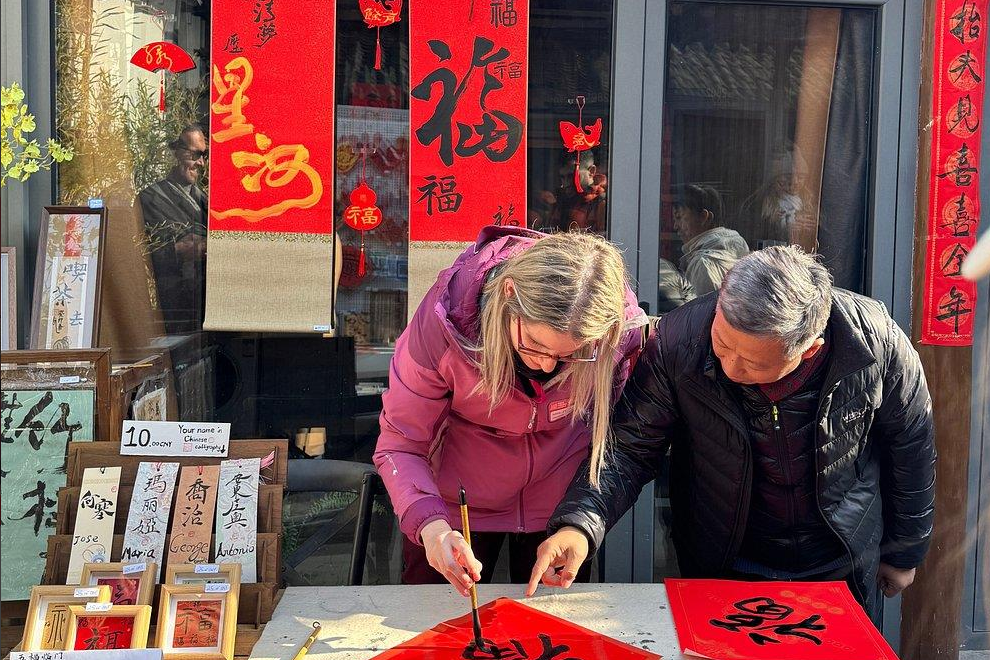 A traveler learning Chinese calligraphy with a local artist